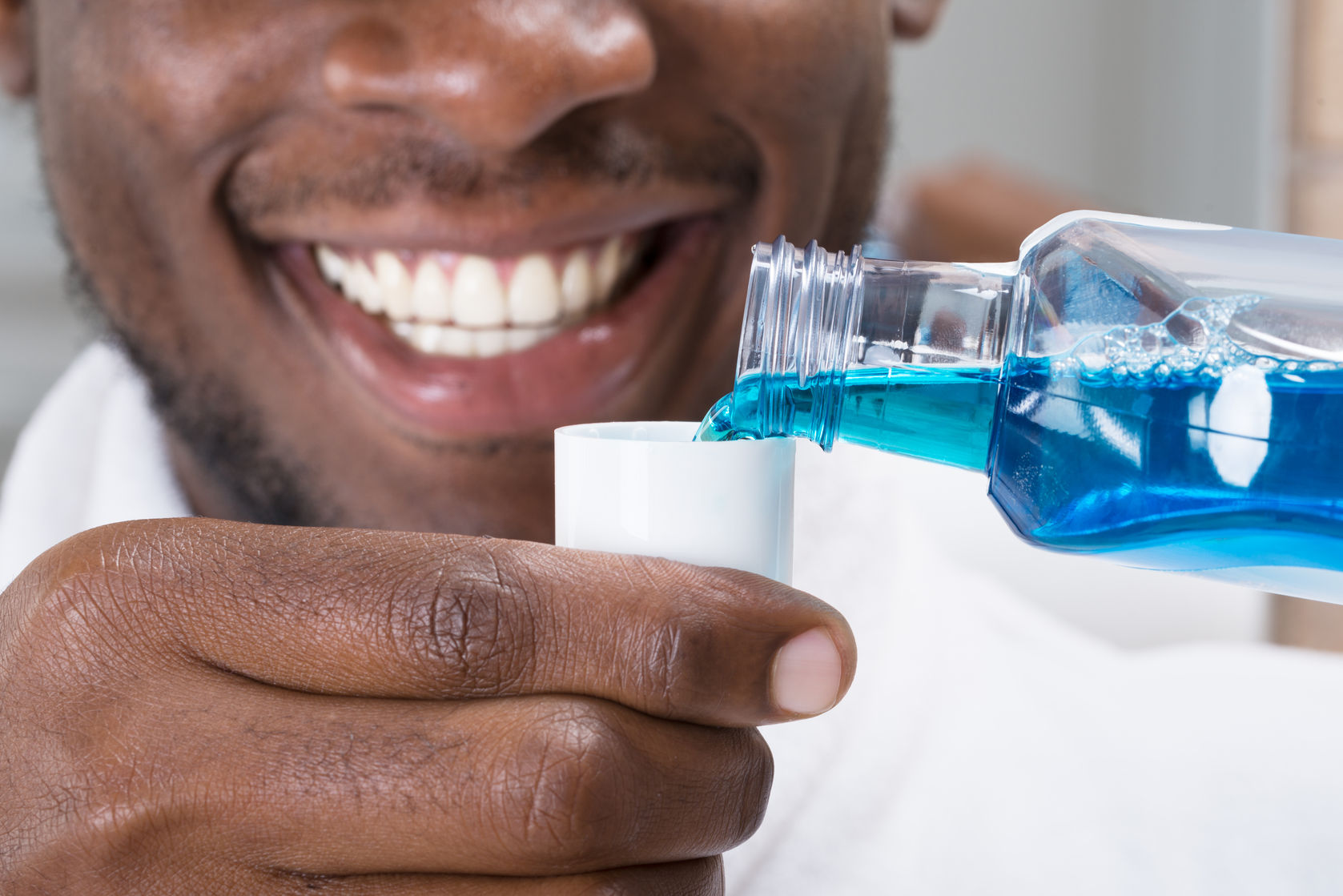 61134869 - close-up of a smiling african man pouring mouthwash into cap