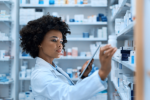 A pharmacist in a white lab coat checking medications on a shelf