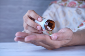 A woman tipping some tablets from a medication bottle into her hand