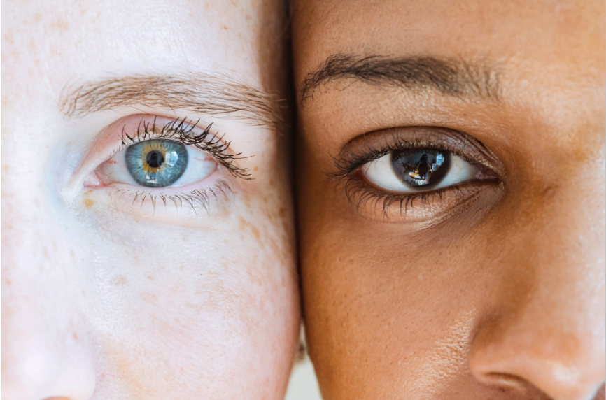Two women, one White one Black,  with their faces next to each other, only their eyes in the picture